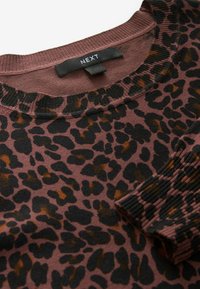 Leopardų rašto megztinis rudos ir juodos spalvos atspalviuose, su įrimuotu kaklu ir rankogaliais, pagamintas iš minkštos medžiagos, užtikrinančios komfortą. Matomas prekės ženklas.