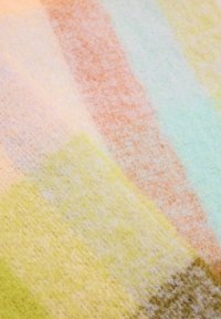 Tissu multicolore avec une texture douce et duveteuse ; présente des rayures pastel dans des teintes de rose, vert, jaune et orange.