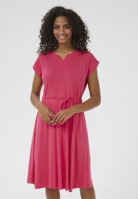 Robe rose à manches courtes avec un décolleté en V, dotée d'une taille ceinturée et d'une jupe fluide qui arrive juste au-dessus du genou. Texture de tissu lisse.
