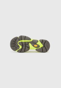 Shoe sole with black rubber tread and neon yellow sections, showing Vibram branding on the center and heel areas.