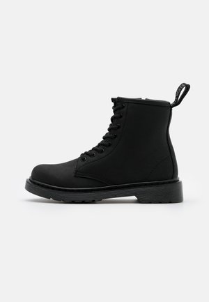 Bottine noire à lacets en matériau synthétique lisse, avec un bout rond, une semelle épaisse et une languette au niveau du talon.