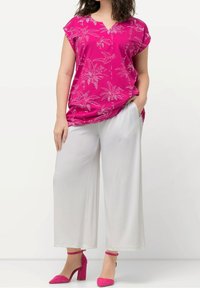 Haut fuchsia à manches courtes avec imprimés de palmiers blancs, associé à un pantalon blanc à jambes larges et des chaussures à talons blocs roses.