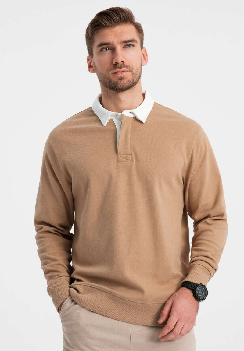 Beige Pullover mit langen Ärmeln und weißem Kragen, ausgestattet mit einer halben Knopfleiste am Hals und gerippten Bündchen. Glatte Textur und entspannte Passform.