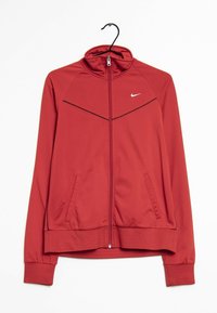 Chaqueta deportiva roja, diseño con cremallera completa, cuello alto, dos bolsillos laterales, detalles en negro en los hombros, presenta el logo de Nike en el pecho.