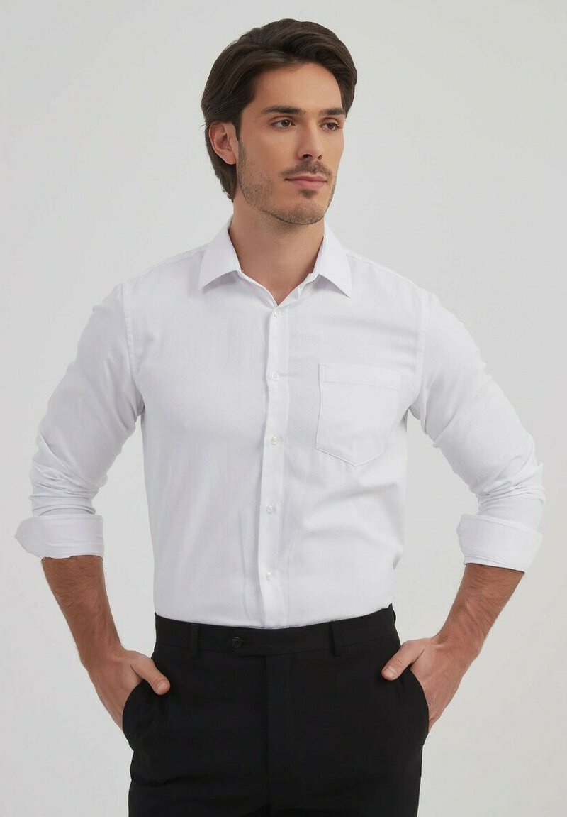Chemise blanche à boutons avec une poche, manches longues retroussées au niveau des coudes, associée à un pantalon noir. Tissu lisse et design de col classique.