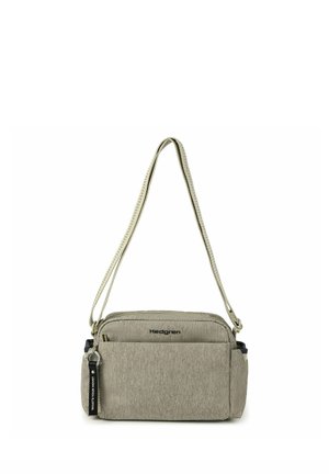 Sac bandoulière rectangulaire en tissu beige avec poche avant, logo de marque noir, sangle réglable et porte-clés noir sur fond blanc.
