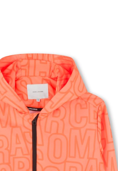 Neon oranje hoodie met een ritssluiting, groot tekstpatroon in een contrasterende kleur en een capuchon met trekkoord. De stof lijkt glad en lichtgewicht.