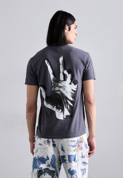 Grijze katoenen t-shirt met een grote zwart-wit handafbeelding op de rug. Zachte textuur met een klassieke pasvorm en korte mouwen.