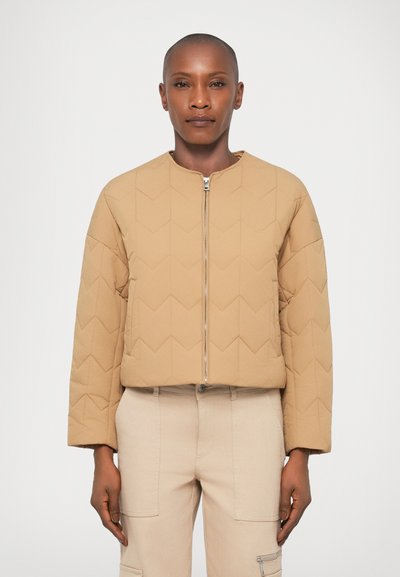 Beige gesteppte Jacke mit Rundhalsausschnitt und vorderem Reißverschluss. Besitzt ein geometrisches Muster und ein kurzes Design. Glatte Textur und lässige Passform.
