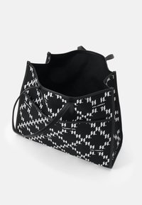 Sac fourre-tout en tissu noir avec un motif abstrait blanc et un logo embossé. Ouverture supérieure, deux poignées et texture lisse.