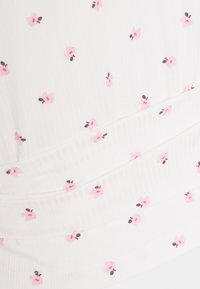 Bílá látka s žebrovanou strukturou, na které se nacházejí malé rozptýlené růžové květy a zelené listy. Hladký, přiléhavý střih s detailním nařasením.