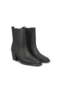 Botas negras de cuero hasta el tobillo con una textura suave, punta afilada y acentos de ribetes en los lados. Tacón grueso y sutil detalle metálico en la punta.