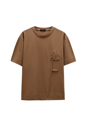Brązowy t-shirt wykonany z bawełny z teksturowanym, kwiatowym wzorem po lewej stronie, z okrągłym dekoltem, krótkimi rękawami i luźnym krojem.
