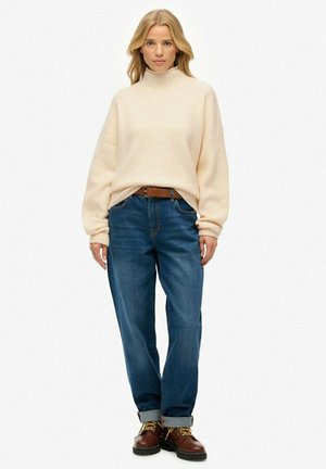 Lys beige strikket turtleneck sweater, afslappet pasform, med mørkeblå high-waisted jeans og brune snørebåndsstøvler. Denim har en klassisk pasform.