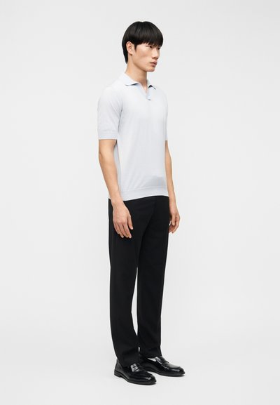 Világoskék rövid ujjú galléros póló, klasszikus gallérral, szabott fekete nadrággal és fényes fekete elegáns cipővel párosítva.