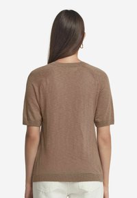 Brun kortärmad stickad tröja med rundad halsringning, ribbad nederkant och subtil textur. Lättviktig tyg, designad med raglansärmar.