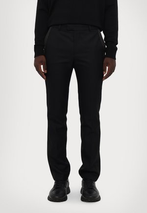 Pantaloni neri su misura con vestibilità slim, texture liscia e vita con intagli. Presentano tasche laterali e dettagli posteriori discreti.