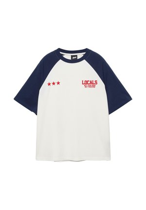 Bela raglan majica s kratkimi rokavi, mornarsko modrimi rokavi in ovratnikom, rdečim motivom s tremi zvezdami ter napisom »LOCALS NOT YOUR HOME NOT YOUR WIN« na prsih.