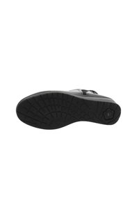 Semelle noire d'une chaussure présentant un motif texturé et un accent floral ; forme incurvée avec un bord supérieur lisse.