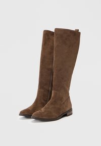 Botas altas de ante marrón hasta la rodilla con tacón plano, que cuentan con un zipper lateral, punta afilada y textura suave.