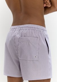 Csíkos fürdőnadrág levendula és fehér pamutból, rugalmas derékkal, oldalsó zsebekkel és egy gombos hátsó zsebbel.