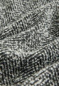 Grå og sort herringbone-stof med en tekstureret overflade, der har små hævede fibre. Stoffet fremstår blødt og tæt.