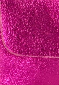 Tela metálica fucsia con una superficie texturizada, que presenta líneas finas visibles y un borde cosido, creando una apariencia vibrante.