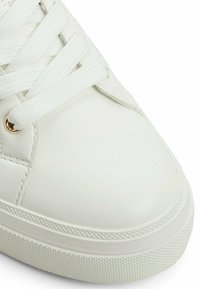 Sneaker bianca in pelle con punta rotonda, suola in gomma testurizzata e lacci piatti. Presenta occhielli in tono oro e una finitura liscia.