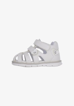 Witte kindersandalen met gesloten neus, gemaakt van synthetisch materiaal. Voorzien van klittenbandsluitingen en decoratieve hartaccenten.