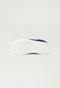 Semelle en caoutchouc blanche avec un motif texturé. Tige bleu foncé en matériau lisse, présentant un design simple et un bout rond.