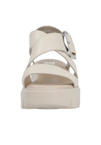Sandales à plateforme beiges avec de larges sangles croisées et une boucle en argent brillant. Semelle texturée avec un léger motif de grip pour l'adhérence.