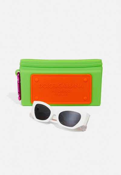 Pochette en silicone verte avec plaque logo orange, fermeture éclair et accents en rose, accompagnée de lunettes de soleil blanches avec des verres foncés.