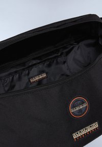 Borsa nera con esterno testurizzato, chiusura a zip e interno liscio. Presenta toppe con marchio in arancione e nero per l'identificazione.