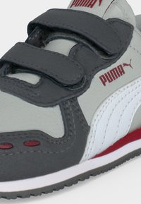 Παιδικό αθλητικό Puma σε γκρι, άσπρο και κόκκινο με δύο ρυθμιζόμενους ιμάντες με βέλκρο και λογότυπο Puma στο πλάι και στη γλώσσα.
