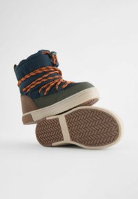 Waterdichte winterlaarzen in donkerblauw en olijfgroen. Voorzien van oranje veters, bruine accenten en een gestructureerde rubberen zool voor grip.