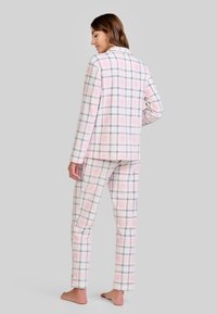 Set de pijama a cuadros en rosa pastel, blanco y gris, que incluye una camisa de botones de manga larga y pantalones a juego, elaborados con tejido suave.