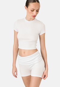 Biely rebrovaný krátky rukáv crop top s logom "LAMANIA" a zodpovedajúcimi vysokými šortkami. Mäkko hladká textúra, priliehavý dizajn.