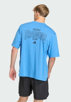 T-shirt bleu à manches courtes avec "ADIDAS TRAINING CLUB" imprimé en noir au dos. Le matériau semble lisse, la coupe est décontractée, assortie à un short noir.
