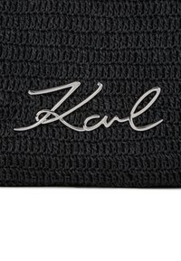 Fekete kötött bélelt sapka, textúrált anyagból készült, a fronthoz kiemelten elhelyezett ezüst színű "Karl" feliratú fémes logóval.
