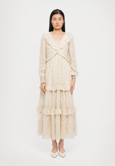Robe longue de couleur beige clair avec un motif floral, volants aux manches et à l'ourlet, et un décolleté en V. Le tissu semble transparent et superposé.