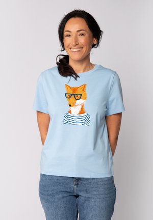 T-shirt en coton bleu clair avec un graphique d'un renard orange portant des lunettes bleues et une chemise rayée. Design à manches courtes et col rond.