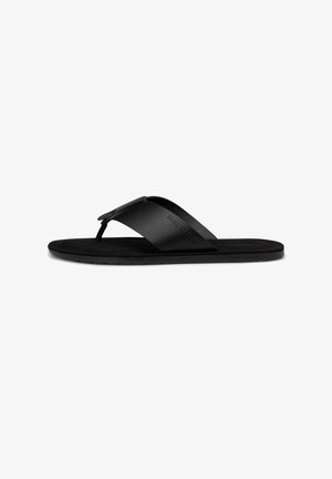 Black flat flip-flop sandal with wide strap and toe post, featuring subtle embossed brand name on the side of the strap.