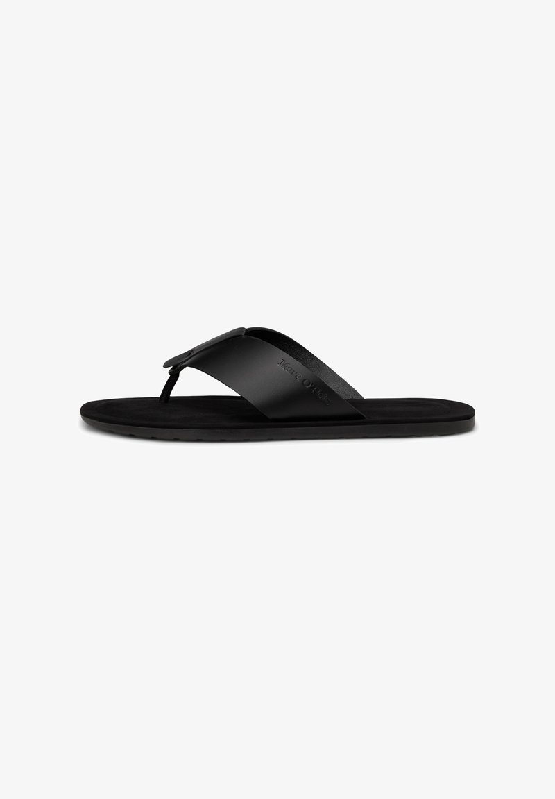 Sandale tongs plates noires avec large bride et entre-doigt, comportant un nom de marque subtilement en relief sur le côté de la bride.