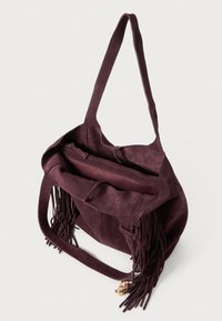 Burgundy suede tote bag with long fringe accents, a single shoulder strap, and a main zippered compartment, featuring an inner pocket.