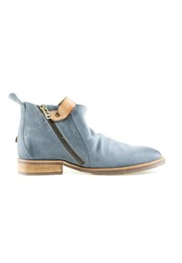 Bottine en daim bleu avec fermeture éclair latérale, languette en cuir marron clair et semelle en bois sur fond blanc.