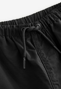 Svarta shorts med elastisk midja och dragsko med metallspetsar, tillverkade av ett slätt och lätt tyg.