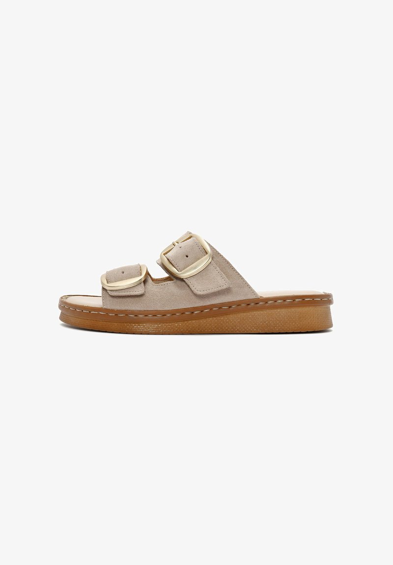 Beige suède slide sandalen met twee verstelbare banden, gouden hardware en een gestructureerde bruine rubberen zool. Stiksels op de bovenkant.