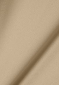 Tessuto beige con una texture liscia e una leggera lucentezza. Presenta un motivo a coste sottile, mostrando un colore caldo e uniforme in tutto il tessuto.