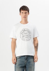 Hvit bomulls t-skjorte med rund hals og et grafisk logo i svart, med teksten "JACK & JONES", "PREMIUM" og "NEW YORK CITY".