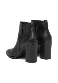 Botines de cuero negro con tacones gruesos y cremalleras traseras, mostrando las vistas posterior y lateral sobre un fondo blanco.